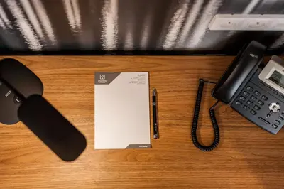 a desk with a phone and a pen and a paper at K4 APARTHOTEL KRAKÓW in Kraków