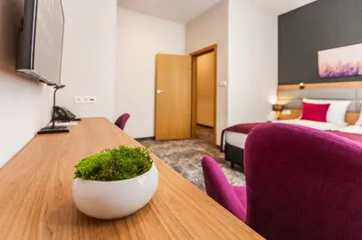 a hotel room with a table and purple chairs at K4 APARTHOTEL KRAKÓW in Kraków