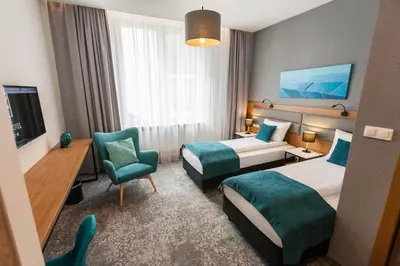a hotel room with two beds and a chair at K4 APARTHOTEL KRAKÓW in Kraków