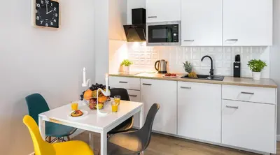 a kitchen with white cabinets and a table and chairs at Vistula Boutique Exclusive Apartments in Kraków