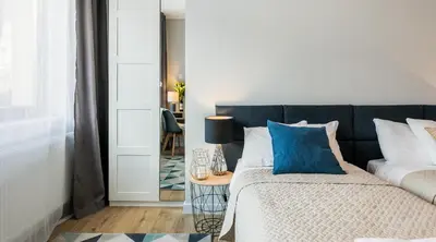 a bedroom with a bed with blue pillows and a table at Vistula Boutique Exclusive Apartments in Kraków