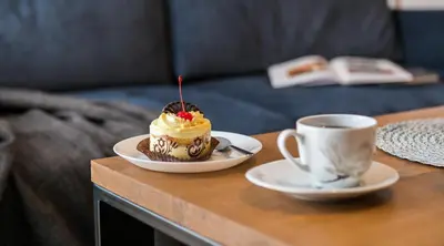 a table with a cake and a cup of coffee at Vistula Boutique Exclusive Apartments in Kraków