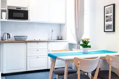 a kitchen with white cabinets and a table and chairs at Househost Apartment - Kupa 2 in Kraków