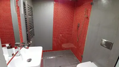 a bathroom with a sink and a shower with red tiles at Mirror Gold & Grey Studios in Kraków
