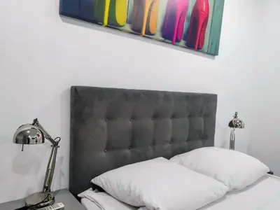 a bed with a black headboard and two lamps at Mirror Gold & Grey Studios in Kraków