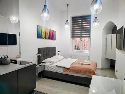 a bedroom with a bed and a kitchen with pendant lights at Mirror Gold & Grey Studios in Kraków