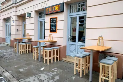 a row of tables and stools outside of a restaurant at Mirror Gold & Grey Studios in Kraków
