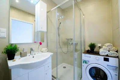 a bathroom with a sink and a washing machine at Romantic Sky Apartment- 15th floor in Kraków
