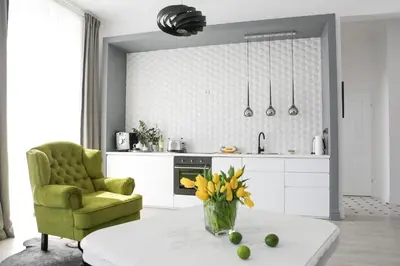 a kitchen with a green chair and a table with flowers at Way2Stay Old Town in Kraków