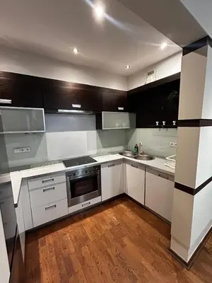 a kitchen with white and black cabinets and wooden floors at SILENT Main Market Square with AC in Kraków