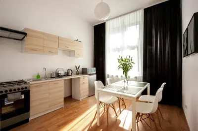 a kitchen with a glass table and white chairs at Agnieszki 1 Apartment in Kraków
