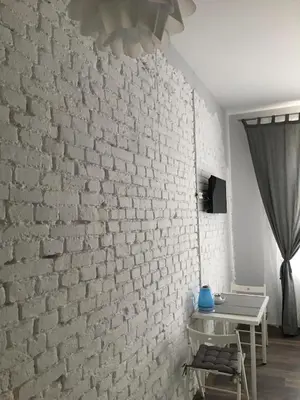 a room with a white brick wall and a table at Ametyst Apartments in Kraków