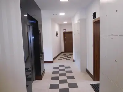 a hallway with white walls and a checkered floor at Apartament DERUBEIS in Wieliczka