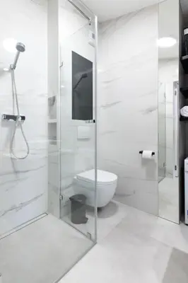 a bathroom with a toilet and a glass shower at Apartament Polka Dots in Kraków
