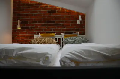 a room with three beds and a brick wall at Apartament Polka Dots in Kraków