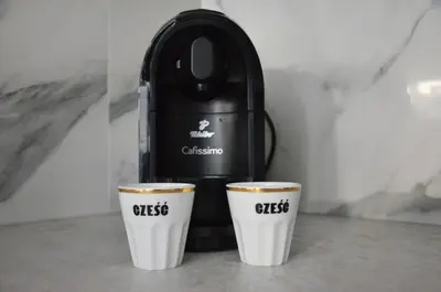 two cups of coffee sitting next to a coffee maker at Apartament Polka Dots in Kraków
