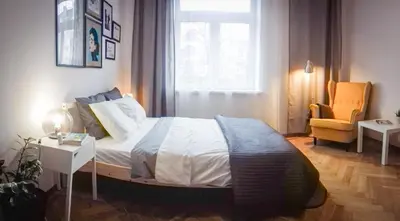 a bedroom with a bed and a chair and a window at SL apartments in Kraków
