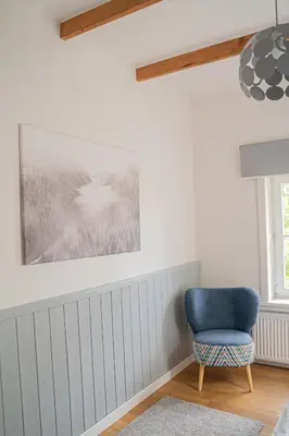 a blue chair in a room with a picture on the wall at Ostoja in Rzyki