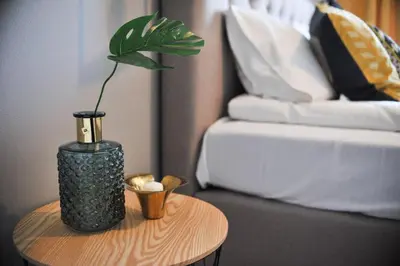 a black vase sitting on a table next to a bed at 3D Szlak 77 Apartament in Kraków