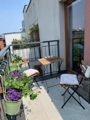 a balcony with two chairs and a table and flowers at 3D Szlak 77 Apartament in Kraków