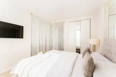 a white bedroom with two beds and a tv at Glossy Apart M45 in Kraków