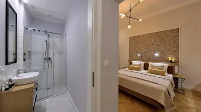 a bedroom with a bed and a shower and a sink at Bentis Luxury Apartments in Kraków