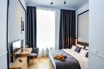 a hotel room with a bed and a desk and a window at Bentis Luxury Apartments in Kraków