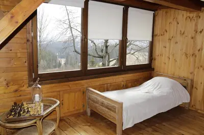 a bedroom with a bed and a table and windows at Buflaczanka in Nowy Targ