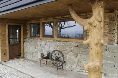 a stone building with a bench and a tree at Buflaczanka in Nowy Targ