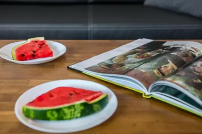 a table with two plates of watermelon and a book at Exclusive Royal Apartments in Kraków