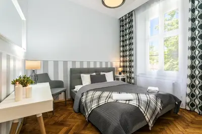 a bedroom with a bed and a desk and window at Exclusive Royal Apartments in Kraków