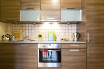 a kitchen with wooden cabinets and a stainless steel oven at Apartamenty i Studia HERBARIUM in Kraków
