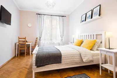 a white bedroom with a bed and a window at Apartamenty i Studia HERBARIUM in Kraków