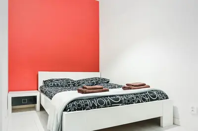 a bed in a room with a red wall at D&A Apartments Old Town in Kraków