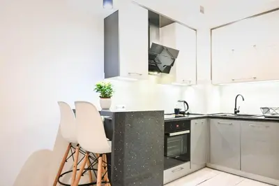a kitchen with white cabinets and a counter with stools at D&A Apartments Old Town in Kraków