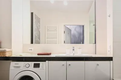 a white bathroom with a sink and a washing machine at D&A Apartments Old Town in Kraków