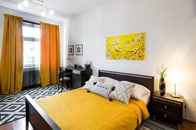 a bedroom with a bed with a yellow blanket and a desk at Cichy apartament obok Wawelu Tarłowska in Kraków