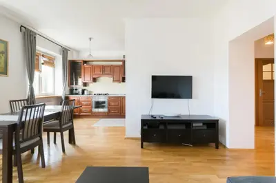 a living room with a dining table and a kitchen at Spacious Apt by Airport Train Old Town in Kraków