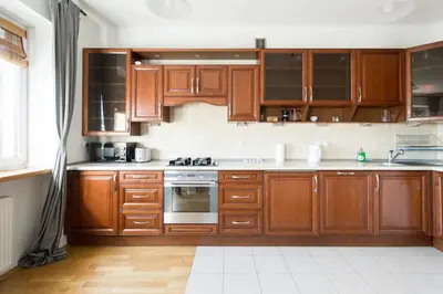 a kitchen with wooden cabinets and a stove top oven at Spacious Apt by Airport Train Old Town in Kraków