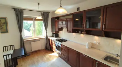 a kitchen with wooden cabinets and a counter top at Spacious Apt by Airport Train Old Town in Kraków