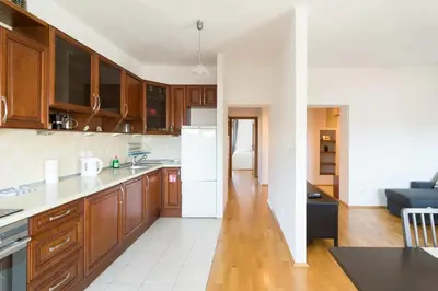 a kitchen with wooden cabinets and a white refrigerator at Spacious Apt by Airport Train Old Town in Kraków