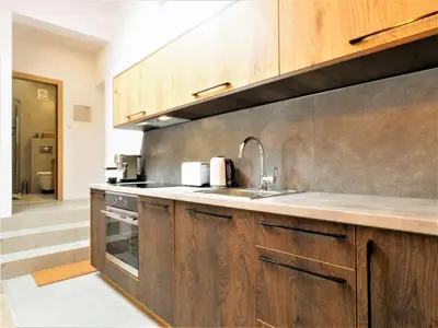a kitchen with wooden cabinets and a sink at Way2Stay Bosacka in Kraków