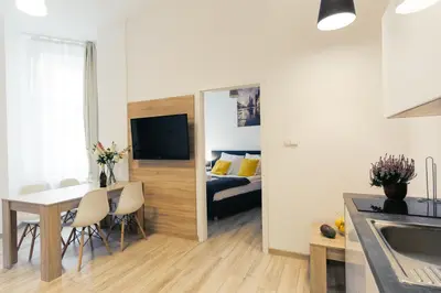 a kitchen and living room with a table and a room with a bed at Way2Stay Bosacka in Kraków