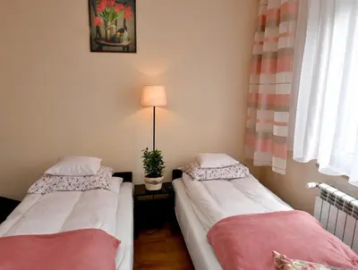 two beds in a room with a lamp and a window at Zator Apartamenty Weekend in Zator