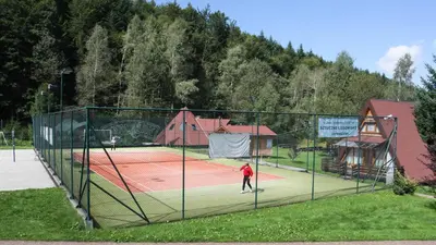 a man is standing on a tennis court at Pokoje w Oberży Czarny Groń in Rzyki
