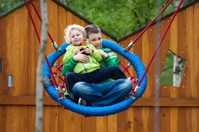 a man and a child sitting in a swing at Pokoje w Oberży Czarny Groń in Rzyki