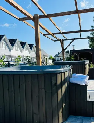 a hot tub on a patio with a pergola at Old Tree Village & Restaurant in Oświęcim