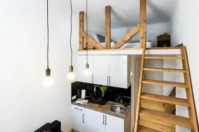 a loft bed in a kitchen with a sink and a ladder at Cracow Best Location Apartment by Cozyplace in Kraków
