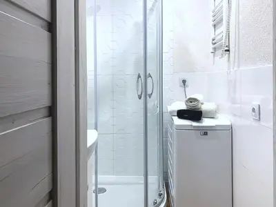 a white bathroom with a shower and a sink at Cracow Best Location Apartment by Cozyplace in Kraków