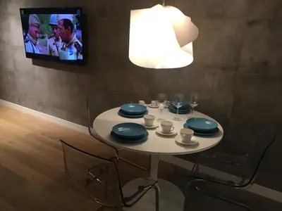 a white table with chairs and a tv on a wall at Apartment in the Gantry Hall - W19 in Kraków